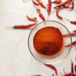 Chili powder and dried peppers on white background